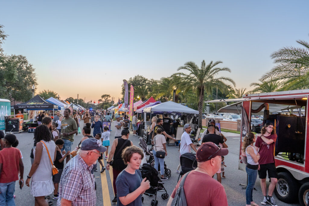 Vibrant scene of people enjoying a community food festival with local vendors, food trucks, and entertainment in Apopka, Florida, promoting community engagement.